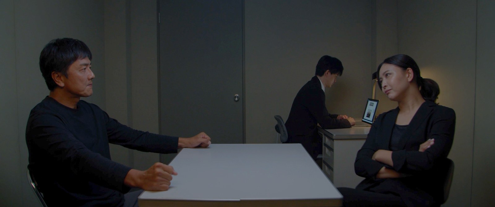 取調室で如月美麗と向かい合う塚本明